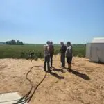 Members of the Better Farm Crops team standing near a spray drone on the edge of a wheat field.