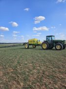 a John Deere tractor pulling a large agricultural sprayer.