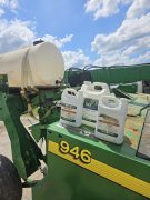 two, one gallon containers of Pro-Serve beside a 2.5 gallon container of Wex sitting on a John Deere 946 mower conditioner