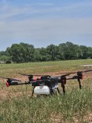 an agricultural spray drone sitting in a field.