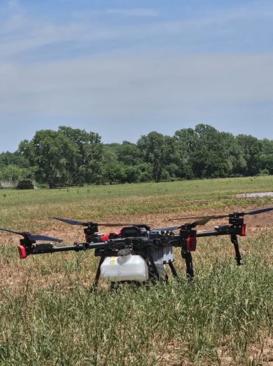 agricultural spray drone sitting in a grazed out wheat field