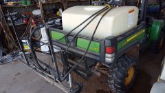 a small sprayer sitting in the bed of a John Deere Gator UTV